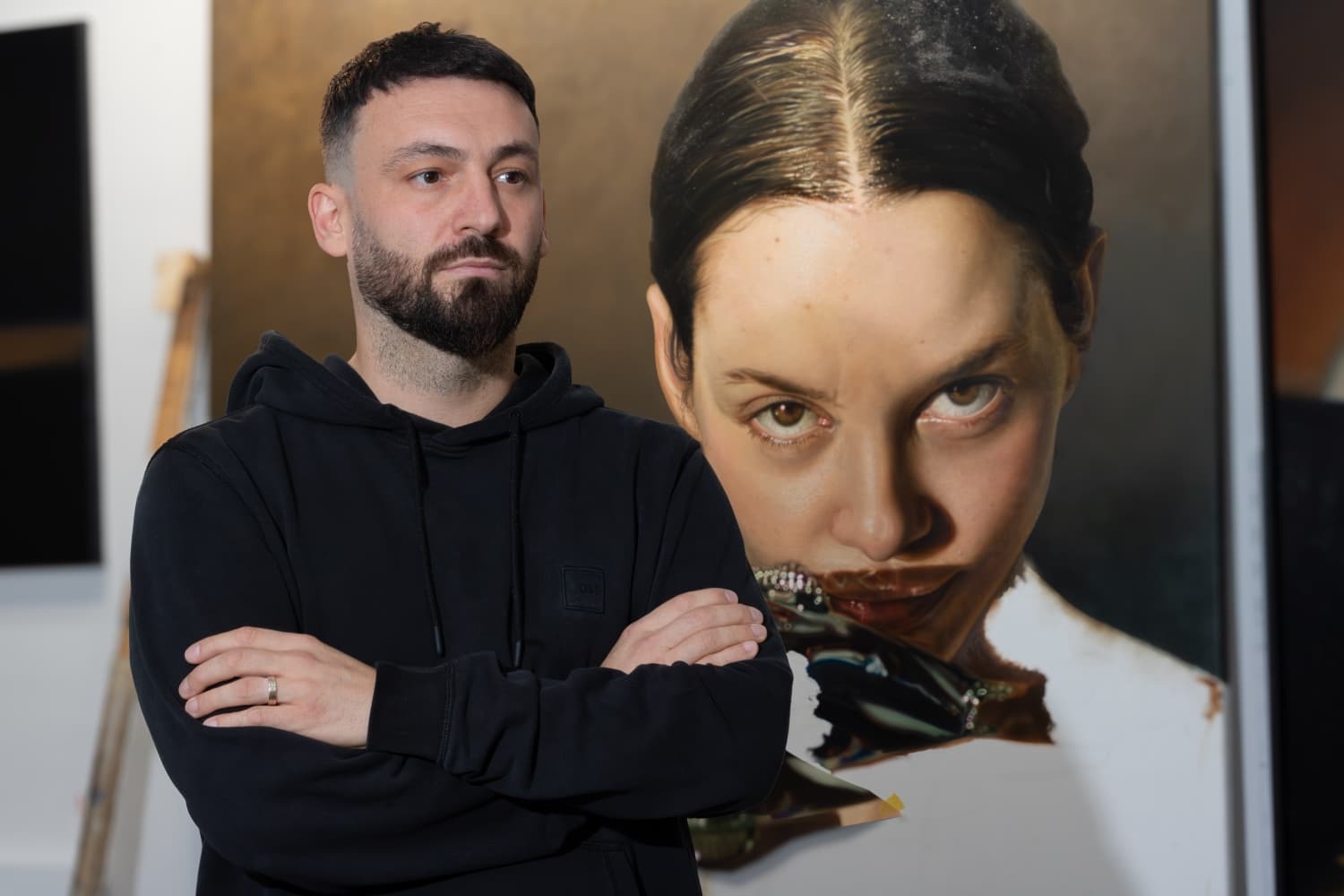Sebastian Nasta, Romanian contemporary painter, in his Cluj-Napoca studio beside a large figurative oil painting