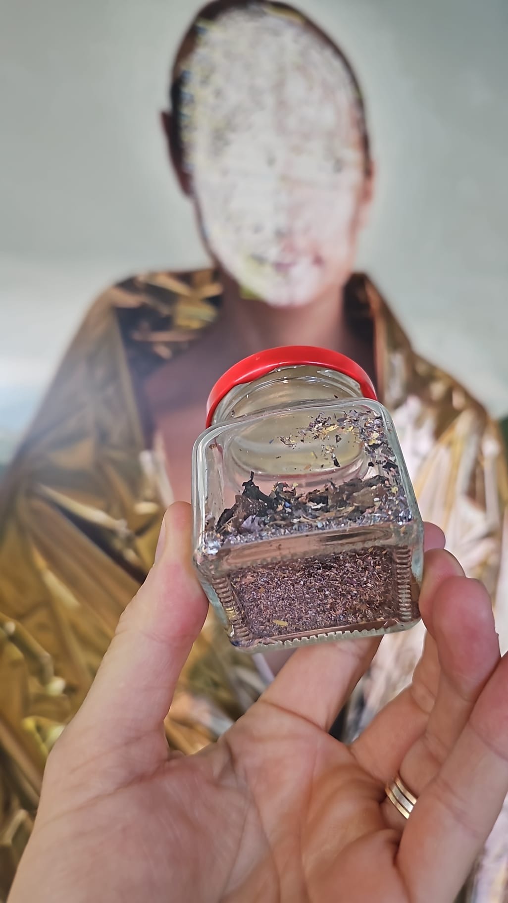 Glass jar containing paint scratched from the portrait